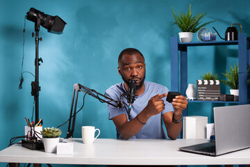 Vlogger presenting npf rechargeable battery pack review pointing at product features sitting at...