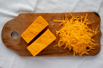 Shredded Sharp Cheddar Cheese on a rustic wooden board, top view. Flat lay, overhead, from above.