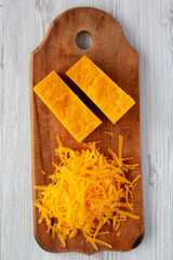 Shredded Sharp Cheddar Cheese on a rustic wooden board, top view. Flat lay, overhead, from above.