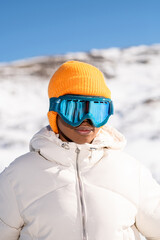 Fototapeta na wymiar A African American woman wearing goggles standing in snowy mountain during winter 
