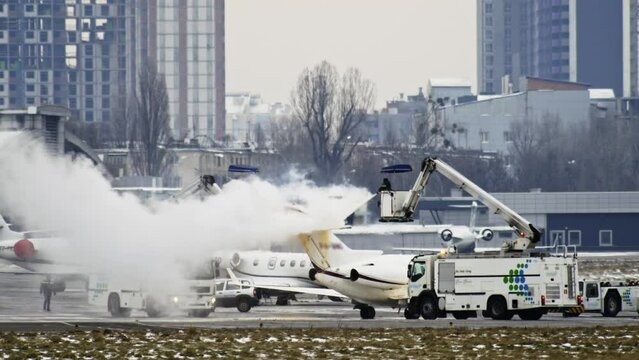 Slow video as special equipment sprinkles a private small plane with antifreeze fluid in the winter from freezing in the air.