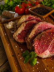 Juicy raw steaks from pork, beef, breaded in spices, on a wooden cutting board. Garlic, herbs, spices. There are no people in the photo. Supermarket, restaurant, hotel, advertising.