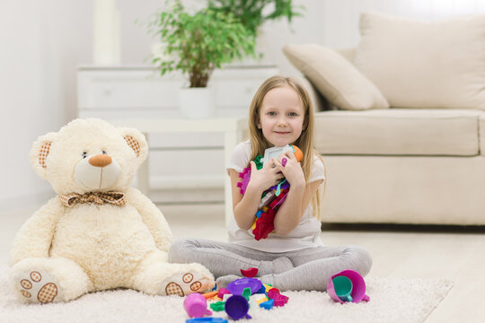 Photo of little girl holding toys on the floor.