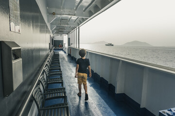 Little boy along chairs on passenger ferry