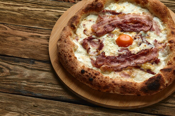 Carbonara pizza with bacon and egg on wooden background