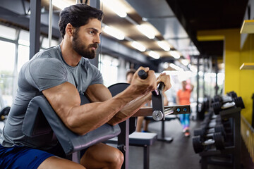 Obraz na płótnie Canvas Muscular bodybuilder handsome man doing exercises in gym. Sport people workout concept