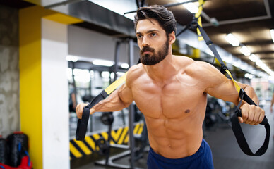 Muscular bodybuilder handsome man doing exercises in gym. Sport people workout concept