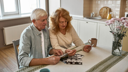 Mature couple looking on old photos at table