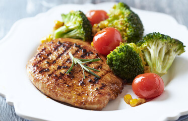 Grilled Turkey Breast with oven baked broccoli, cherry tomatoes and sweet corn. Close up. 