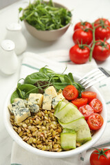 Delicious lentil bowl with blue cheese, tomatoes and cucumber on white table