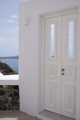 A beautiful whitewashed door with a view to the aegean sea and the blue sky in Santorini Greece