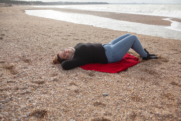 Beatuful woman with over weight body walking in the beach, The plus size model wearing jeans, the warm knitted blanket and sweater. the wind in the bich have fun with hairs