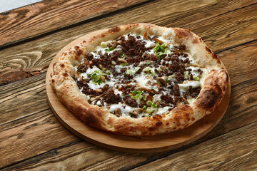 Delicious homemade pizza with mozzarella, mushrooms, beef and chicken. Wooden background, selective focus.