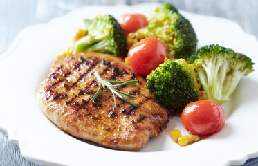 Grilled Turkey Breast with oven baked broccoli, cherry tomatoes and sweet corn. Close up.