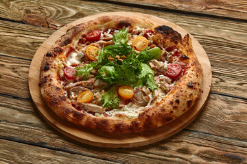 Pizza Caesar. Pizza with chicken, tomato, cheese and lettuce on wooden board. Top view. Free space for your text. Delivery food