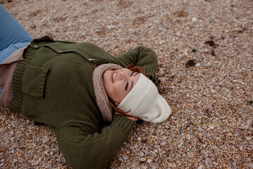 Beatuful woman with over weght body walking in the beach, The plus size model wearing jeans, the warm knitted blanket and sweater. the wind in the bich have fun with hairs