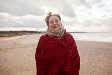 Beatuful woman with over weight body walking in the beach, The plus size model wearing jeans, the warm knitted blanket and sweater. the wind in the bich have fun with hairs