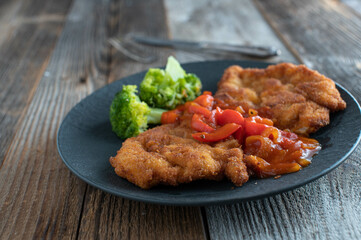 Breaded pork schnitzel with spicy puszta sauce cooked with bell pepper, onions and tomatoes 