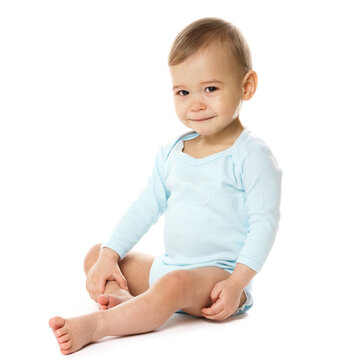 Curious little boy in romper sitting and smiling.