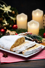 Fototapeta na wymiar Sliced Traditional Christmas stollen cake with marzipan and New Year decorations on wooden background