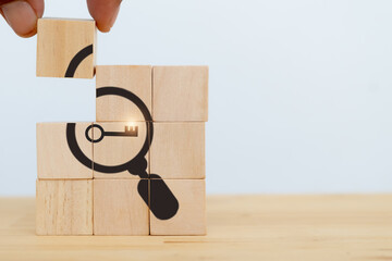 Finding solutions concept. Business problem solving and make decision. New ideas and innovation. Team brainstorming to set strategies. Hand holds wooden cubes with magnifying glass and key icon.