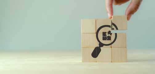Finding solutions concept. Business problem solving, make decision. New ideas and innovation. Team brainstorming to set strategies. Hand holds wooden cubes with magnifying glass and puzzle jigsaw icon - obrazy, fototapety, plakaty