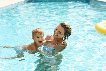 Mother and her cute little son swimming in outdoor pool during summer vacation - Powered by Adobe