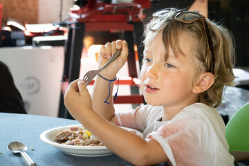 Little boy eating food using fork