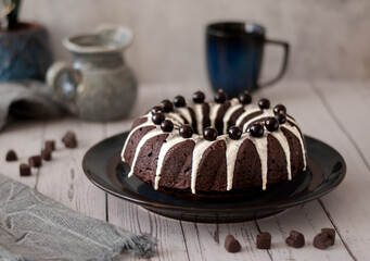 Dark chokolate bundt cake topped with white chokolate glaze and black currant