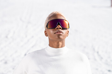 A African American woman with sunglasses sitting on snowy ground during winter