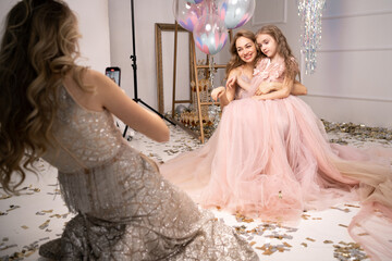 photo session on a smartphone at a professional photo studio. a woman and a child in beautiful long...