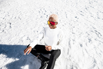 Fototapeta na wymiar A African American woman with sunglasses sitting on snowy ground during winter