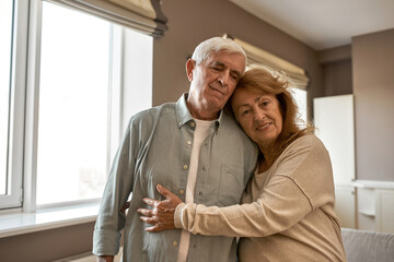 Elderly caucasian couple hug each other at home
