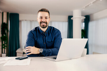 A happy businessman working online from his cozy home and smiling at the camera.