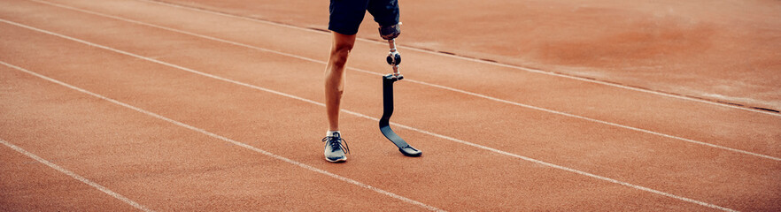 Handicapped runner with artificial leg standing on running track. Legs standing on running track.