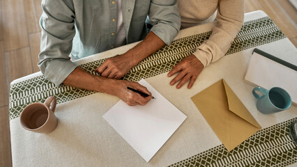 Partial image of man writing letter near his wife