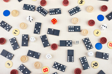 Dominoes, chips, dice and checkers for board games on light table. View from above.