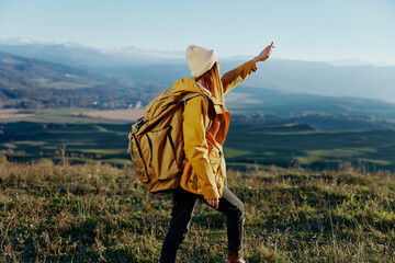 woman traveler in a yellow jacket in a hat backpack travel mountains Lifestyle