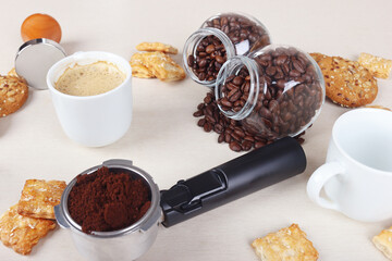 Breakfast with sweets, cup of espresso, coffee beans and ground coffee on table.