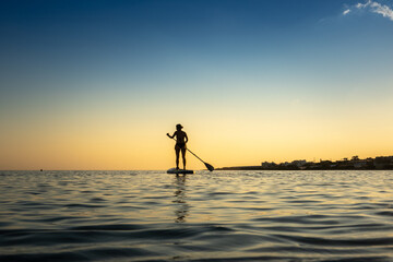 Woman stand up paddle boarding on sea against sky