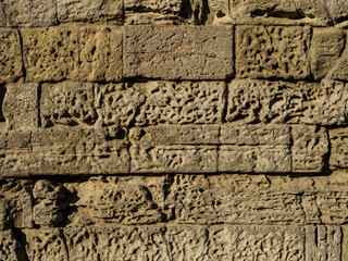 Texture of an ancient stone wall. Pattern of weathered brown bricks. Irregularities and roughness....