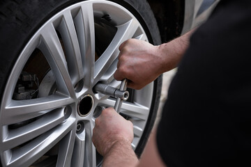 A close up of the man’s hands changing tires on the car