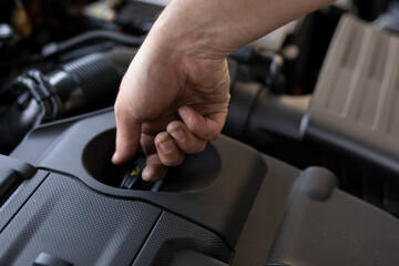 Naklejka premium A close up of the man's hand checking the oil in the car engine