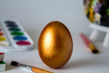 Golden Easter egg on a watercolor background. Simple holiday composition. Symbolism of the Easter egg festival concept. Art work, handmade, creativity with children for decoration for Easter