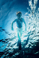 Boy with swimming mask and flippers snorkeling in sea