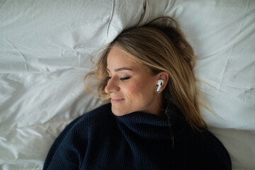 Young woman listening to music with headphones in her ears in her bedroom. High quality photo.