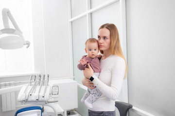 woman with a baby in her arms in a dental clinic. first visit to the dentist