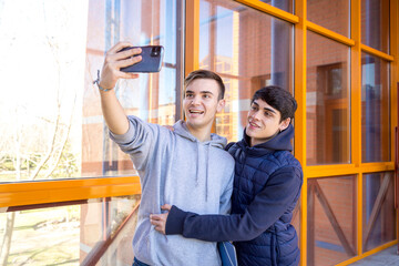 couple gay college boyfriends taking a picture with a cell phone