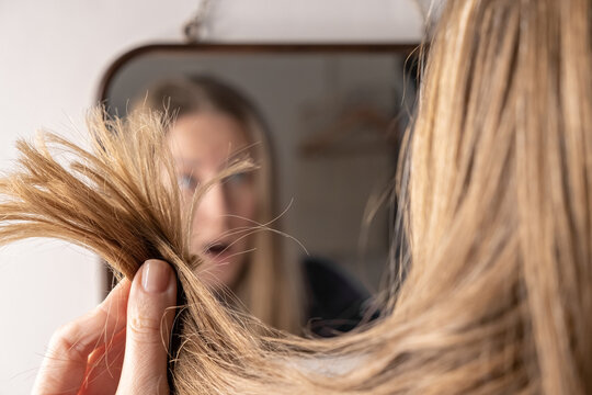 Young Woman In Front Of Mirror Sad Upset With Hair Loss Damage Problem