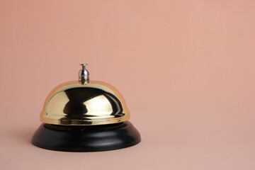 Gilded bell hotel service on pastel beige background, isolated.Conceptual hotel, travel and recreation.